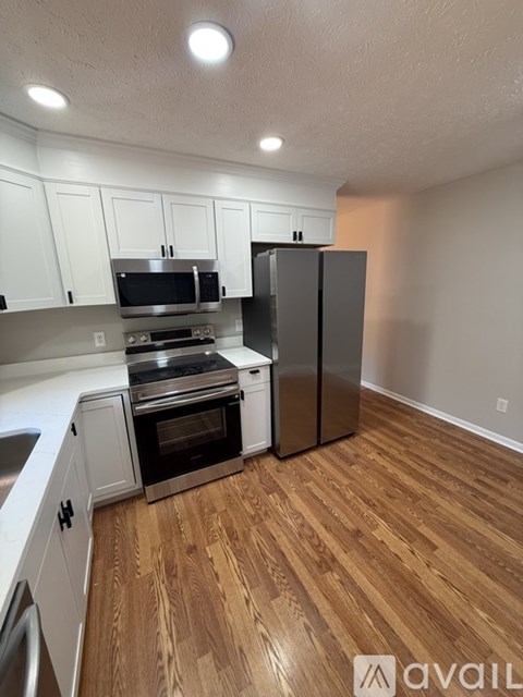A kitchen with wooden floors and white cabinets.