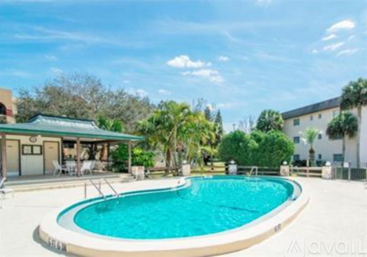 A swimming pool surrounded by a white fence and trees.