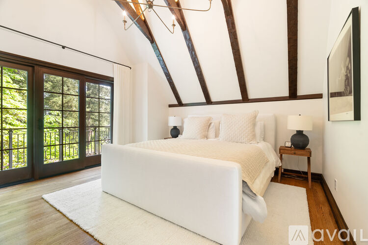 A bedroom with a white bed and a wooden ceiling.