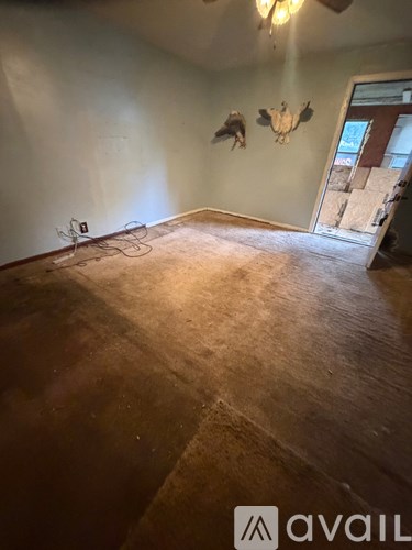 A room with a ceiling fan and a doorway leading to another room.