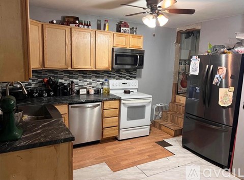 A kitchen with wooden cabinets and a black fridge.