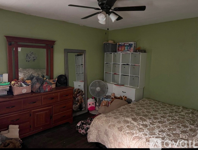 A bedroom with a bed, dresser, and a ceiling fan.