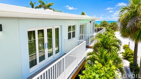 A white house with a balcony overlooking a beach.