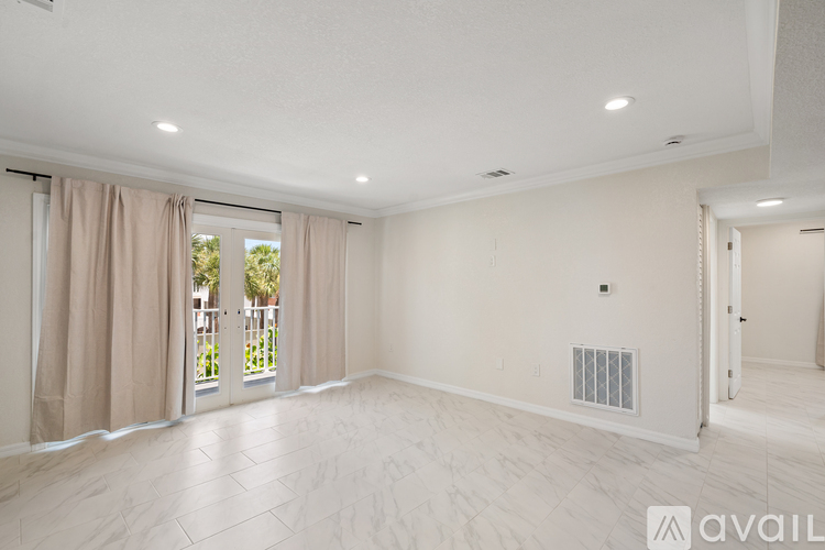 A spacious room with a sliding glass door leading to a balcony.
