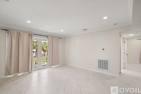 A spacious room with a sliding glass door leading to a balcony.