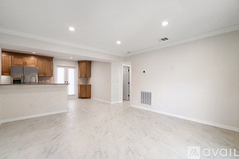 A spacious, empty room with wooden flooring and white walls.