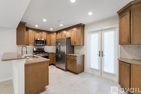 A kitchen with wooden cabinets and a marble floor.