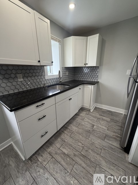 A kitchen with white cabinets and a black countertop.