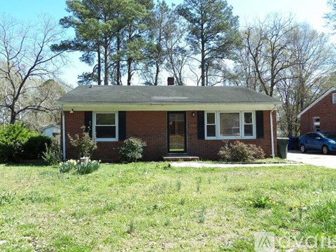 A small brick house with a green lawn in front.