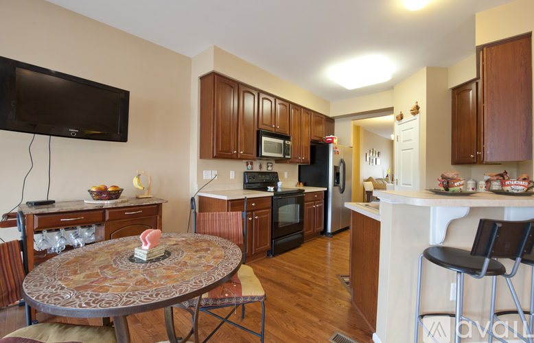 A kitchen with wooden cabinets and a round table with a vase of flowers on it.