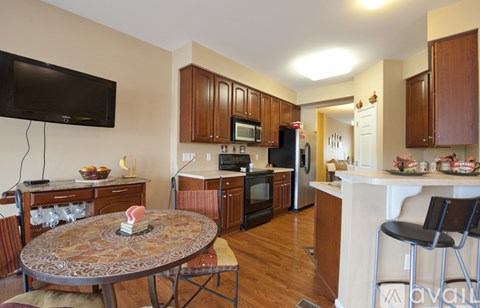A kitchen with wooden cabinets and a round table with a vase of flowers on it.