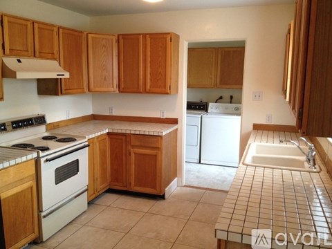 A kitchen with wooden cabinets and a white stove top oven.