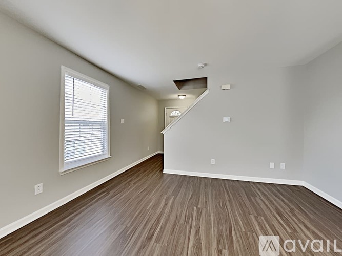 A room with wooden flooring and a window with blinds.