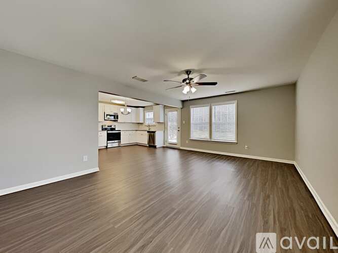 A spacious room with wood flooring and a ceiling fan.