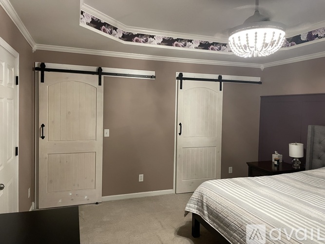 A bedroom with a bed, a nightstand, and a sliding door.