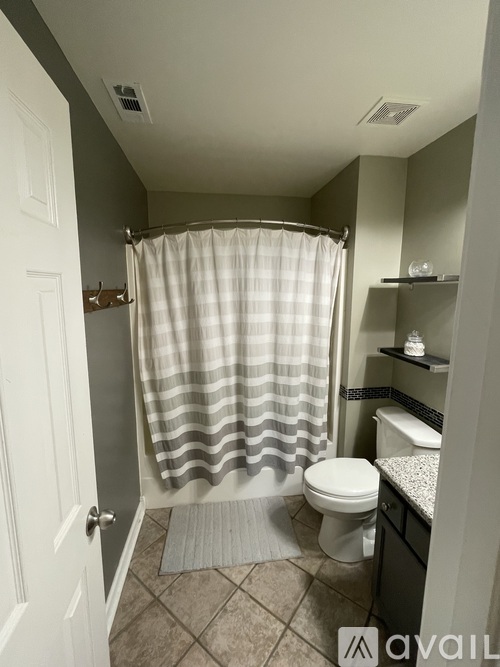 A bathroom with a toilet, a shower curtain, and a towel rack.