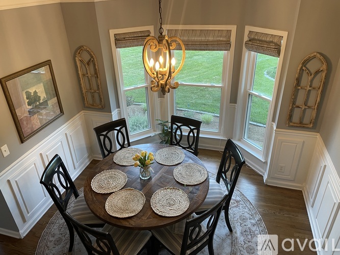 A dining room with a table set for four and a chandelier hanging from the ceiling.