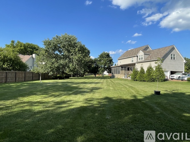 A large, well-maintained lawn in front of a house with a fence and trees.