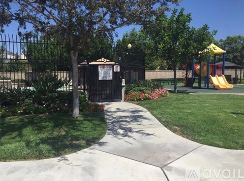 A playground with a yellow slide and a black fence.