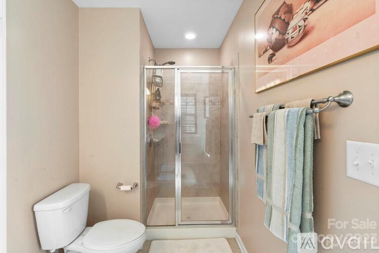 A bathroom with a toilet, a glass shower stall, and a towel hanging on the wall.