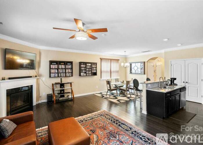 A living room with a fireplace and a kitchen area in the background.