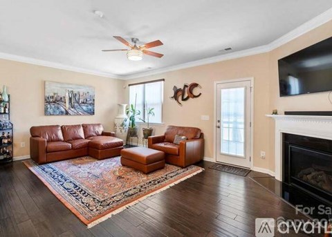 A living room with a brown leather couch and a rug.