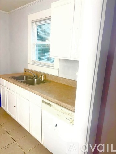 A kitchen with white cabinets and a window above the sink.