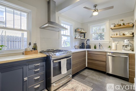A modern kitchen with dark blue cabinets and stainless steel appliances.