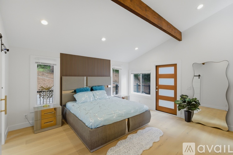 A bedroom with a large bed and a wooden ceiling beam.