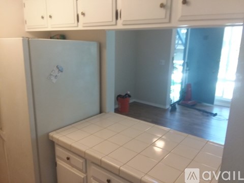 A kitchen with white cabinets and a white fridge.