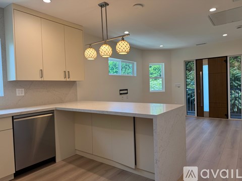 A modern kitchen with a stainless steel dishwasher and a marble island.
