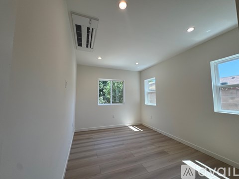 A spacious room with wooden flooring and a window overlooking a tree-filled outdoor area.