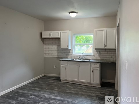A kitchen with white cabinets and a window.