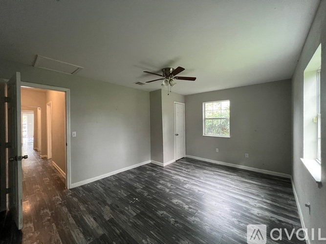 A spacious room with a ceiling fan and wooden flooring.
