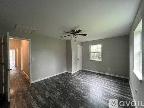 A spacious room with a ceiling fan and wooden flooring.
