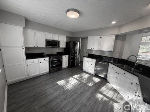 A black and white photo of a kitchen with wooden floors and white cabinets.