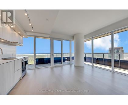 A spacious room with a view of the cityscape through large windows.