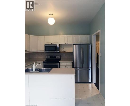 A kitchen with white cabinets and a stainless steel refrigerator.
