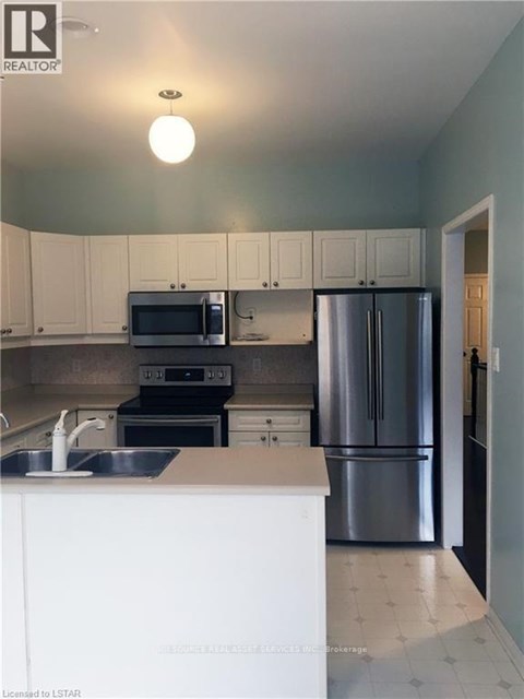 A kitchen with white cabinets and a stainless steel refrigerator.