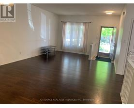 A room with wooden floors and white walls, furnished with a table and chairs.