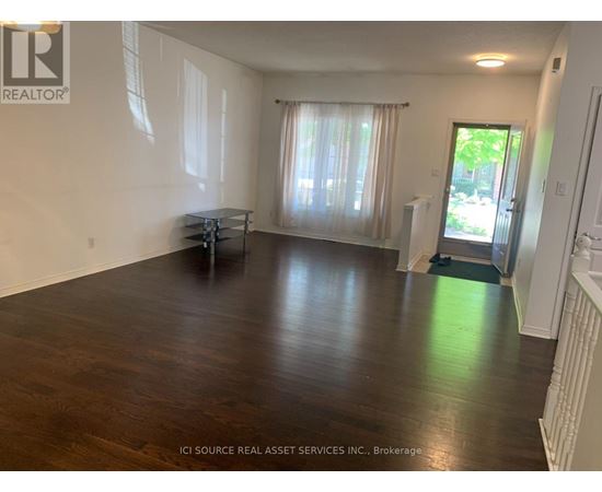 A room with wooden floors and white walls, furnished with a table and chairs.