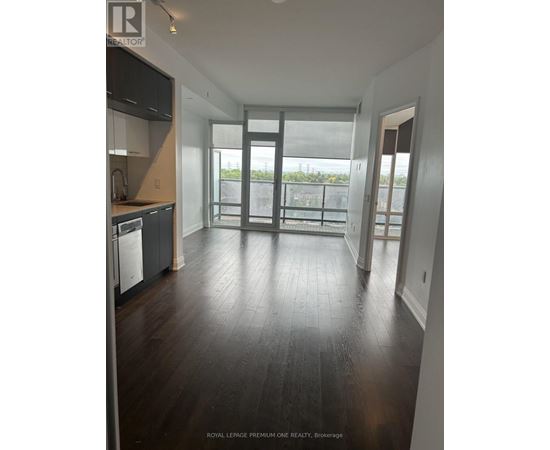 A spacious room with wooden flooring and a large glass door leading to a balcony.