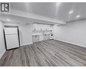 A kitchen with white appliances and cabinets with a wooden floor.