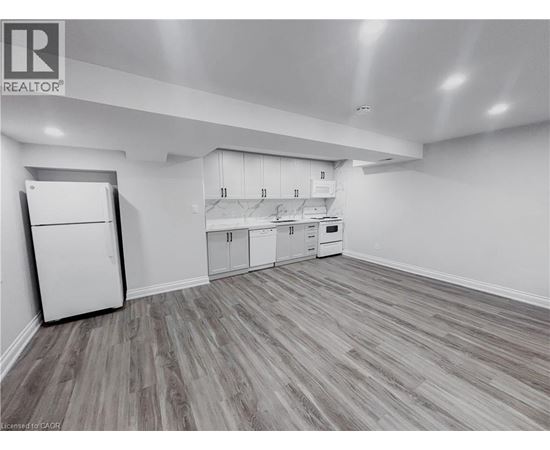 A kitchen with white appliances and cabinets with a wooden floor.
