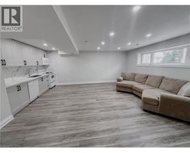 A well-lit, spacious living room with a kitchen area in the background.