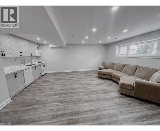 A well-lit, spacious living room with a kitchen area in the background.