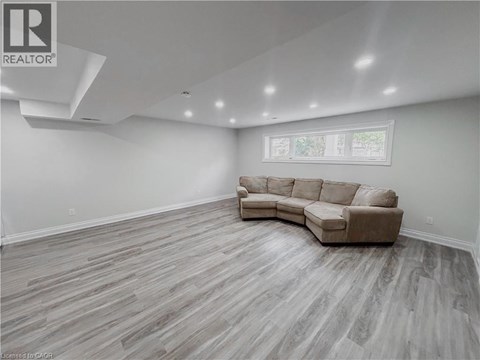 A spacious living room with a large sectional sofa and hardwood flooring.