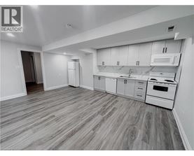 A spacious kitchen with white appliances and wooden flooring.