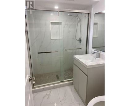 A bathroom with a glass shower stall and a white sink.