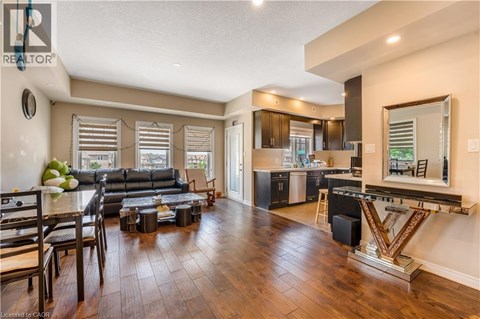 A well-lit, spacious living room with a large black sofa and a wooden floor.